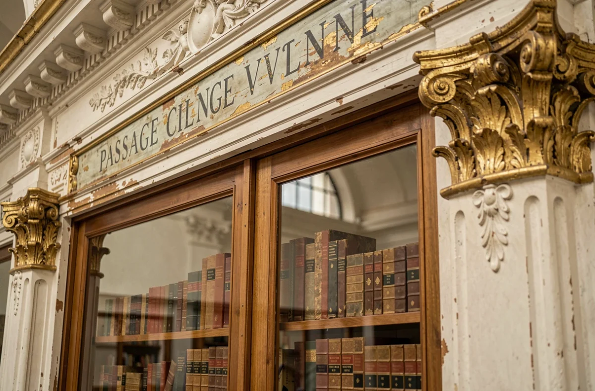 Détail architectural du passage Vivienne, frises en plâtre néoclassiques et vitrine de librairie ancienne avec livres en cuir